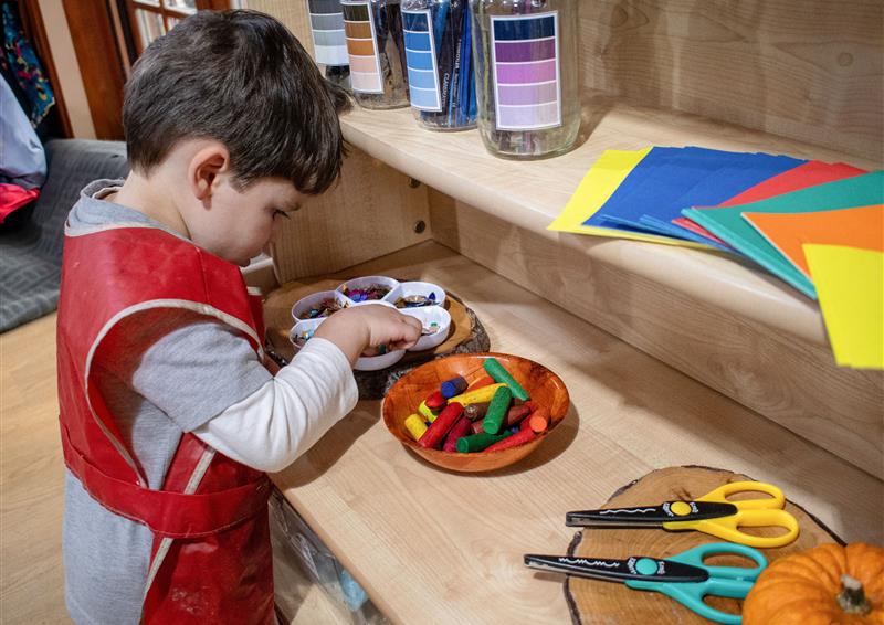 A little boy is gathering art materials from the Millhouse Welsh Dresser.